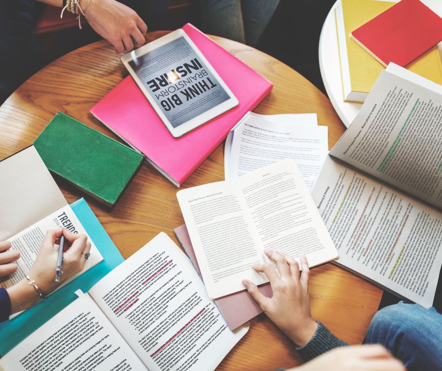 Open reports and notebooks spread across a table during study